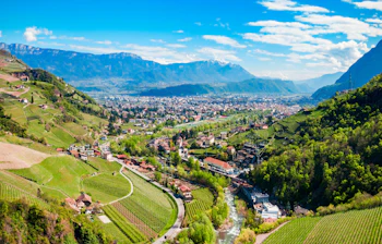 Luftfoto over Bolzano med grønne vingårde, Adige-floden og de majestetiske Dolomitter i baggrunden i Sydtyrol, Norditalien