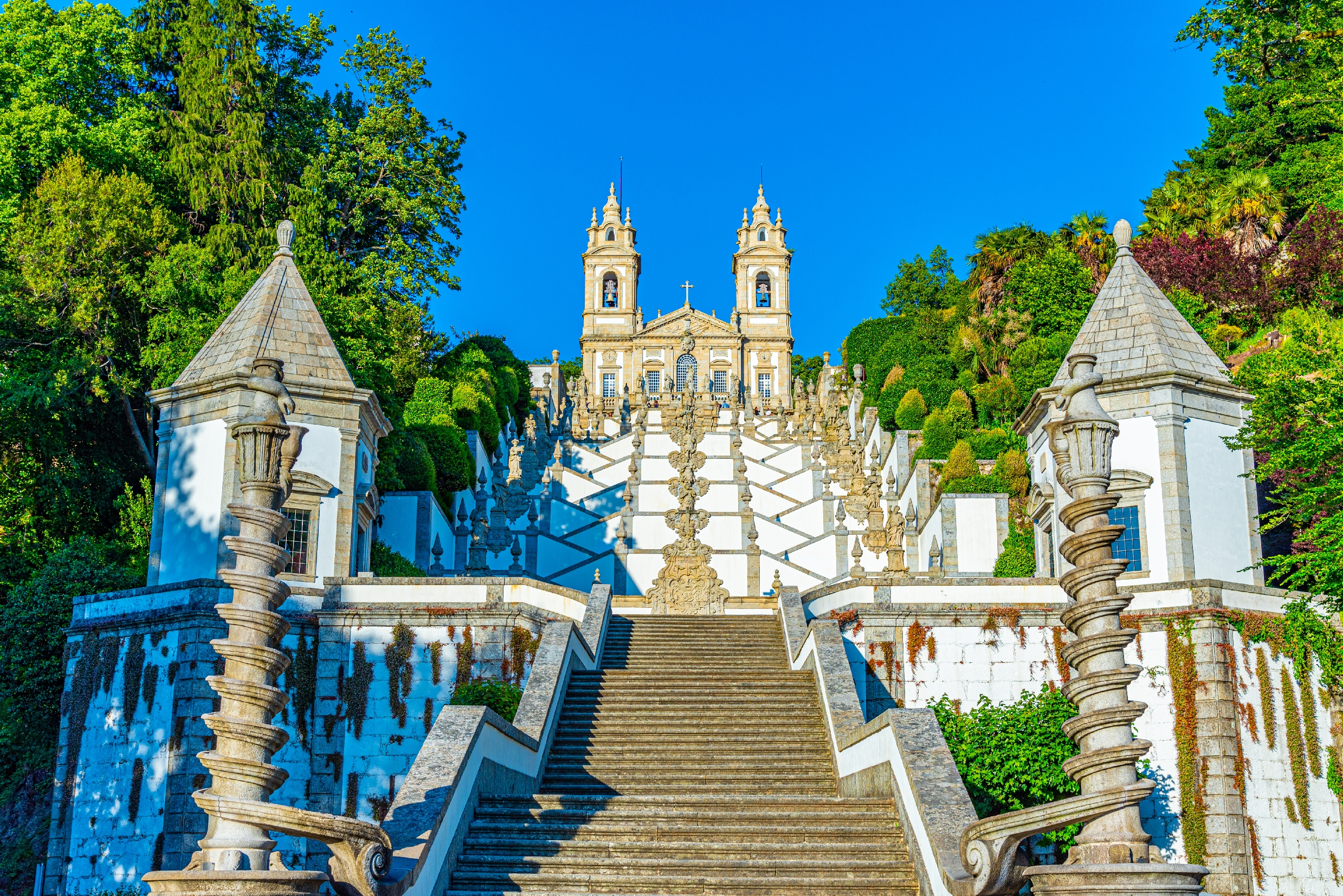 Den berømte barokke trappe til Bom Jesus do Monte helligdom i Braga, Portugal med to tårne omgivet af grøn vegetation