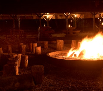 Traditionelt boma-bål der brænder i natten ved Bakubung Lodge i Pilanesberg National Park, hvor gæster kan nyde en autentisk afrikansk middagsoplevelse under stjernerne