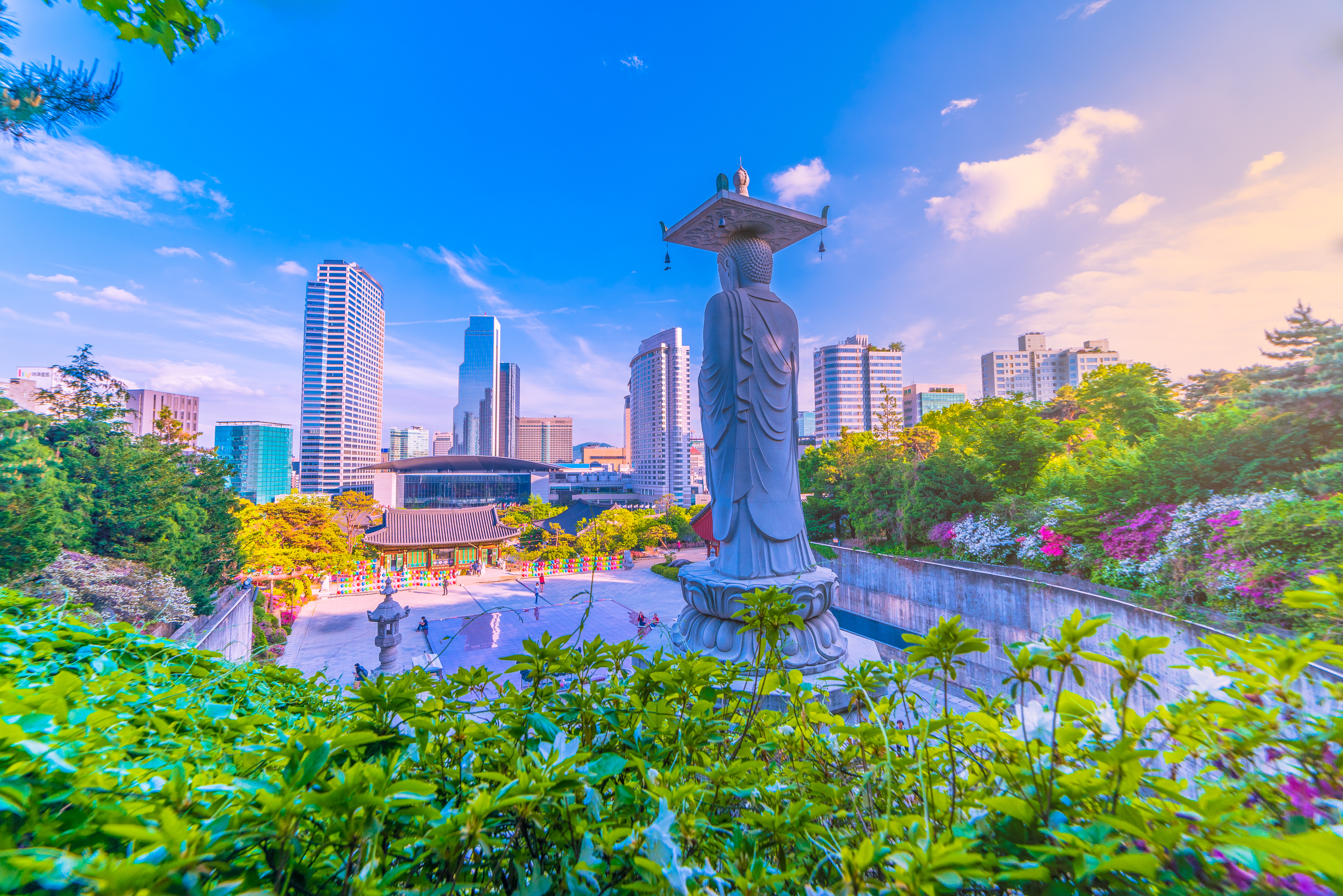 Bongeunsa templet med Buddha statue i forgrunden og moderne skyskrabere i Gangnam distriktet i Seoul, Sydkorea