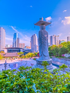 Bongeunsa templet med Buddha statue i forgrunden og moderne skyskrabere i Gangnam distriktet i Seoul, Sydkorea
