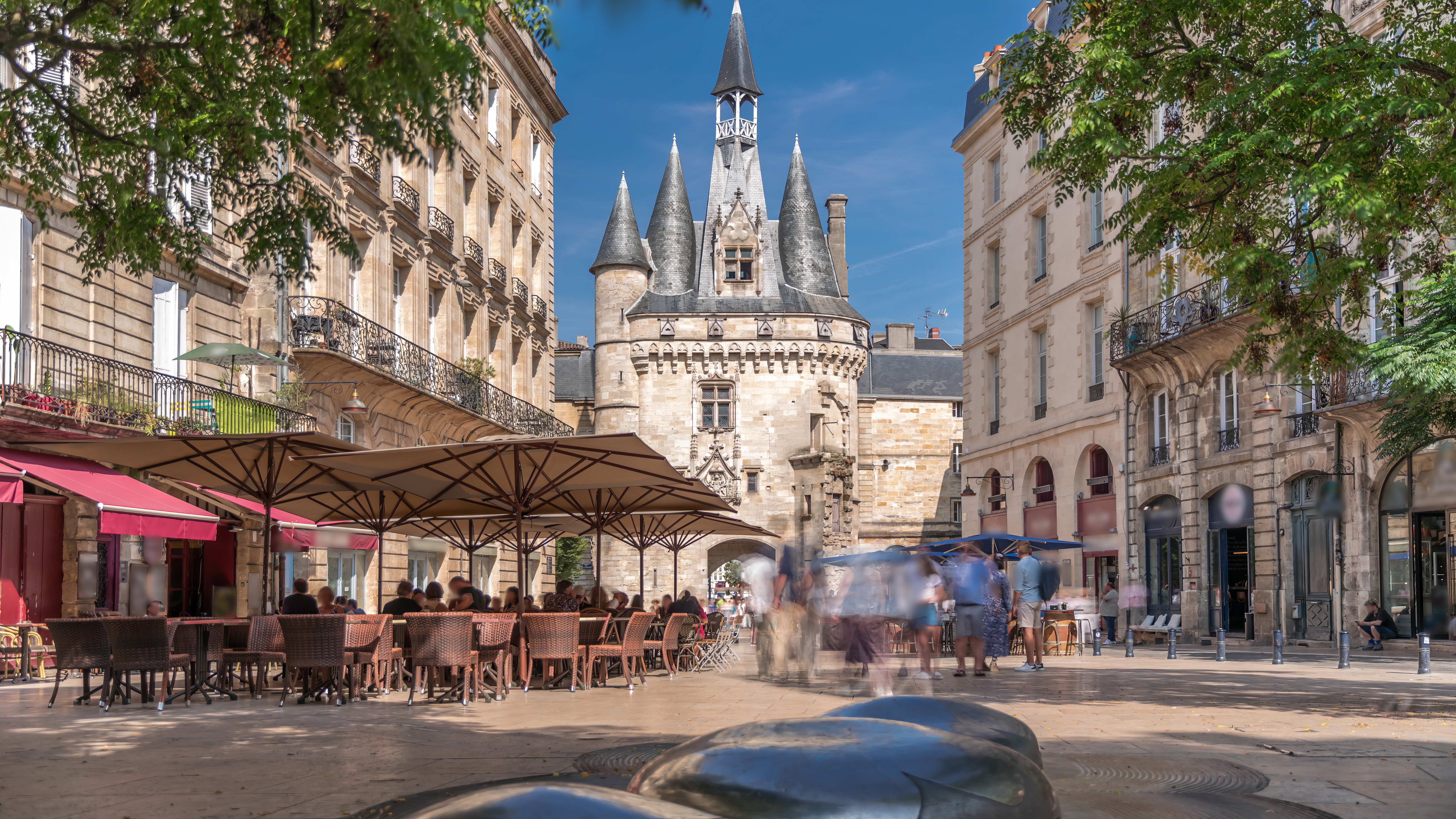 Historiske Porte Cailhau middelalderport i Bordeaux med gotiske tårne og livlige gadecaféer