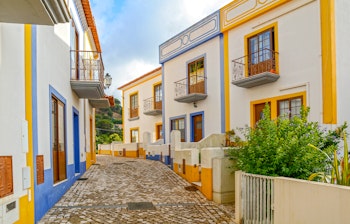 Idyllisk brolagt gade med farverige traditionelle huse i landsbyen Bordeira nær Carrapateira i Algarve-regionen, Portugal
