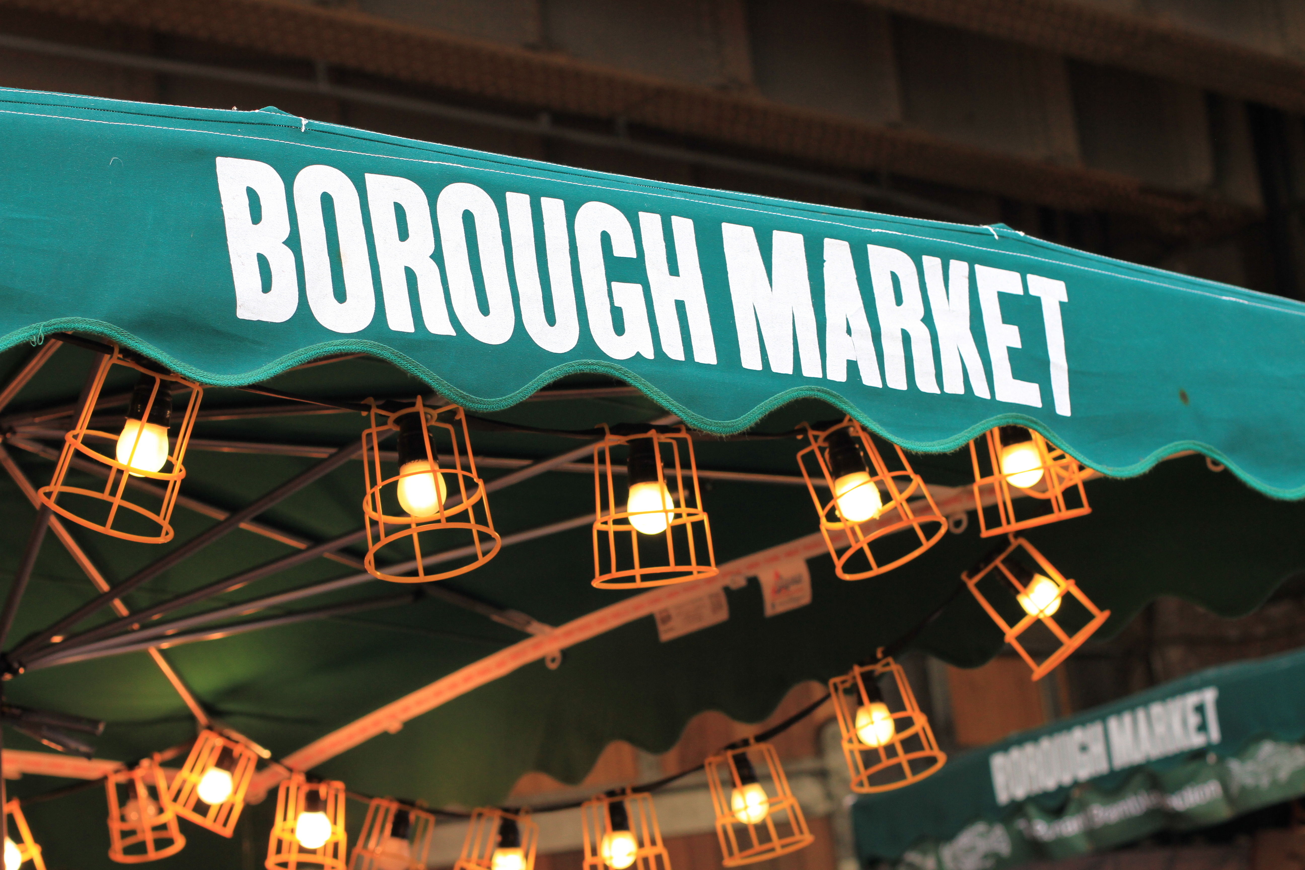 Det livlige Borough Market i London med historiske bygninger og farverige madboder, hvor besøgende kan opleve et væld af internationale kulinariske specialiteter