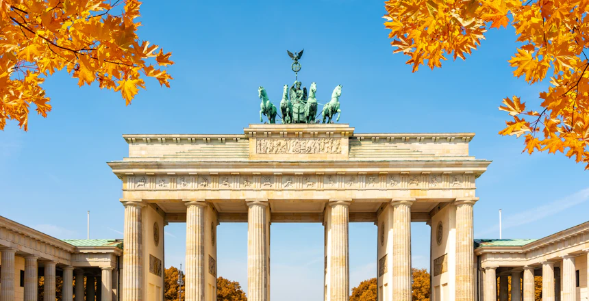 Brandenburg Port i Berlin med gylden efterårsløv og blå himmel