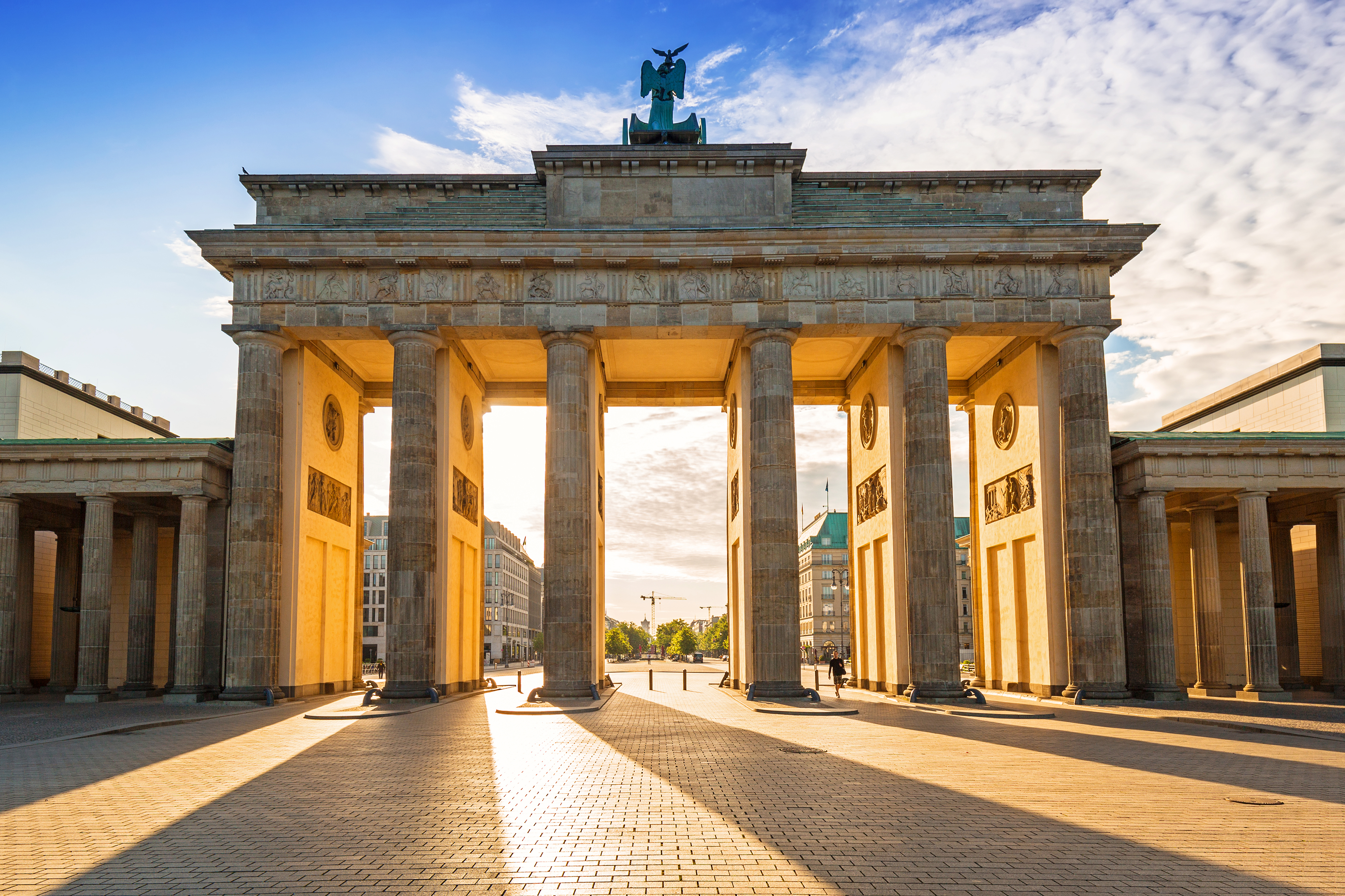 Brandenburg Port i Berlin ved solnedgang med gylden belysning af de klassiske soejler
