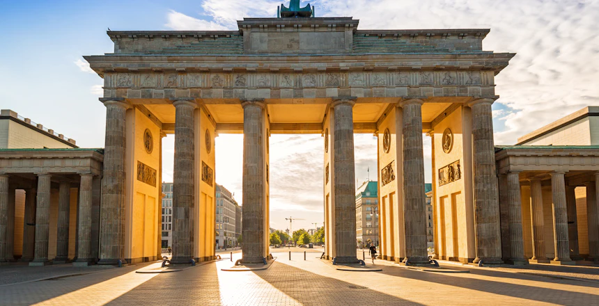 Brandenburg Port i Berlin ved solnedgang med gylden belysning af de klassiske soejler