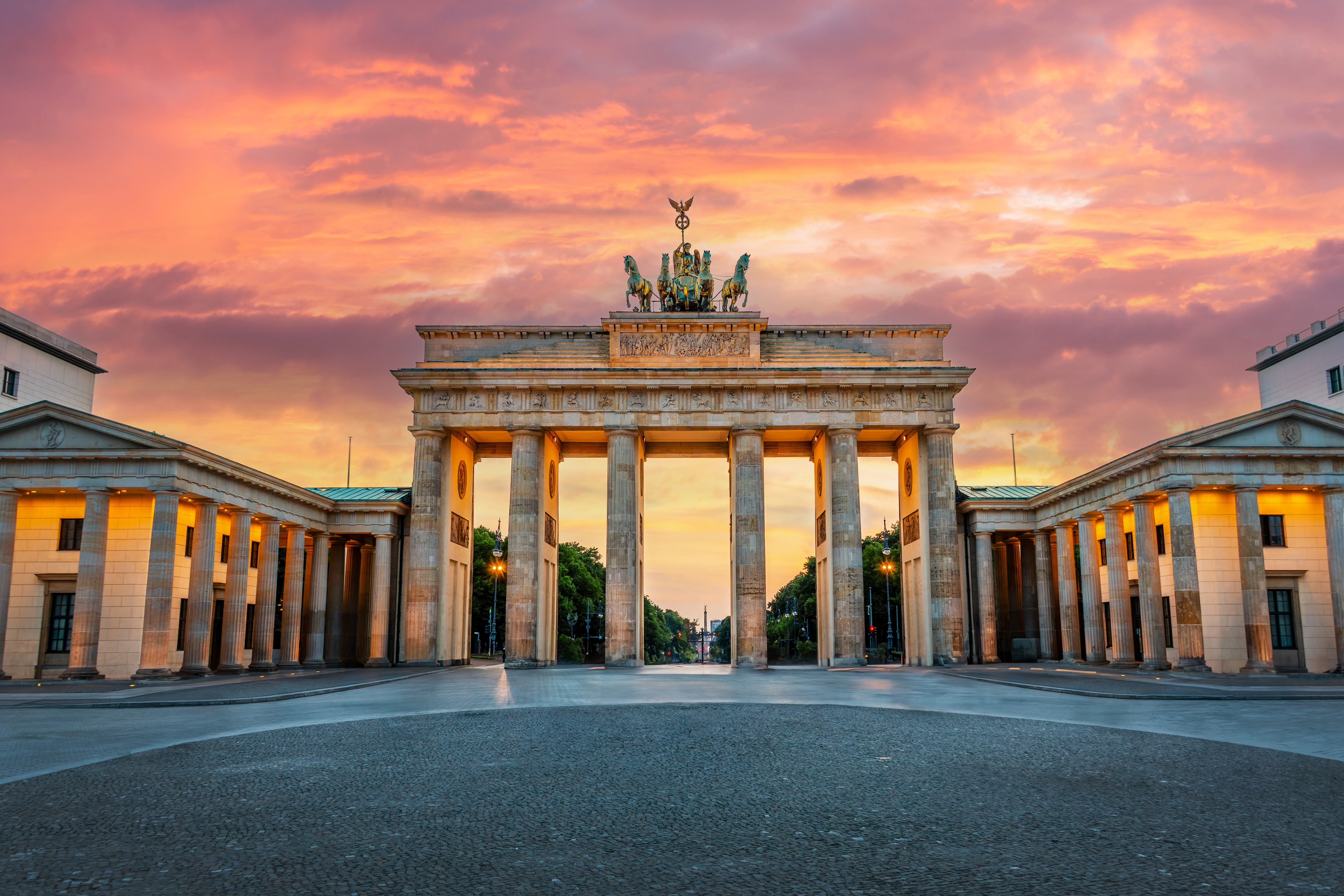 Brandenburger Tor i Berlin belyst ved solnedgang med dramatisk lyserød himmel og klassisk arkitektur