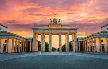 Brandenburger Tor i Berlin belyst ved solnedgang med dramatisk lyserød himmel og klassisk arkitektur