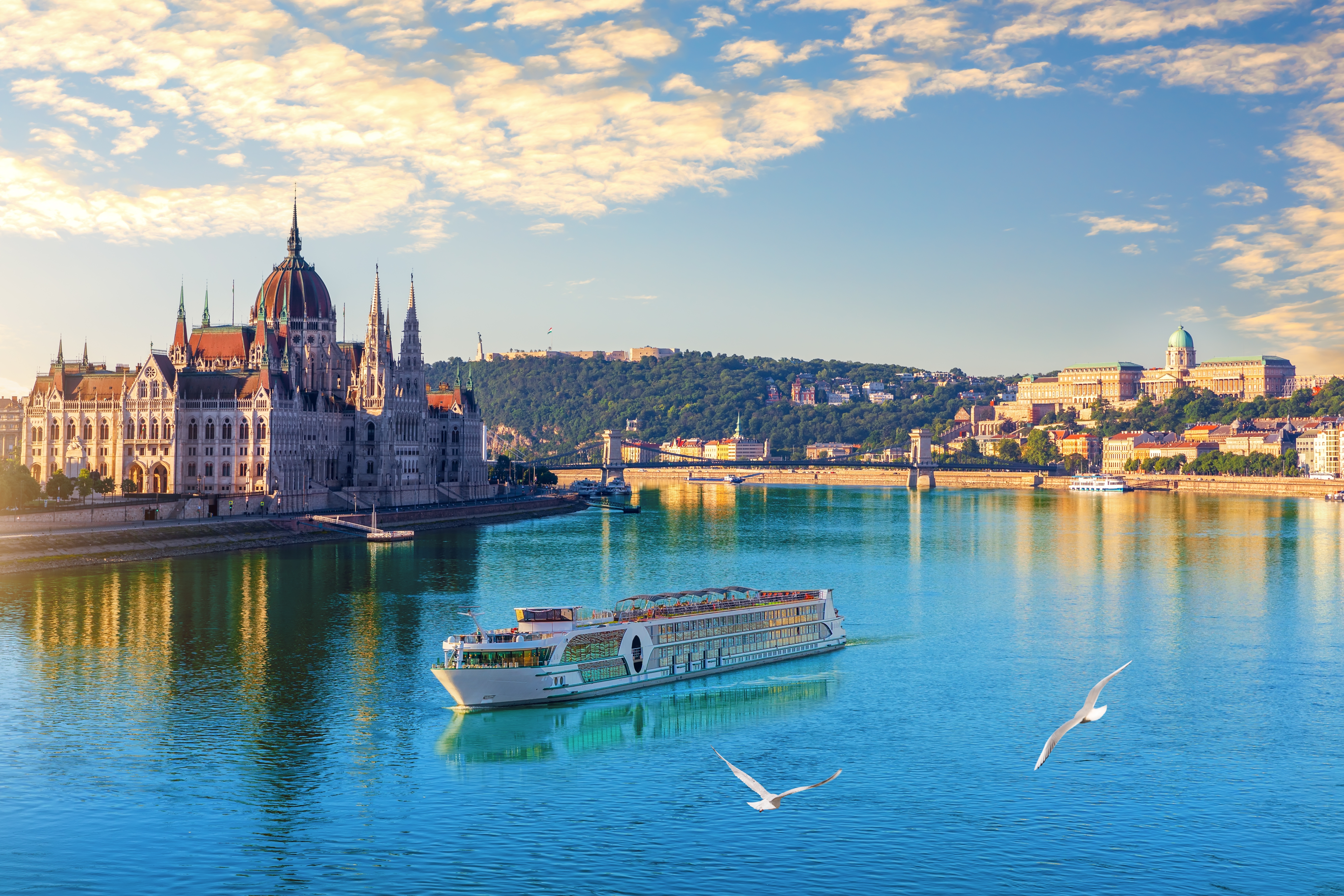 Aftenvy af Ungarns parlament ved Donau i Budapest med cruiseskibe i solnedgang