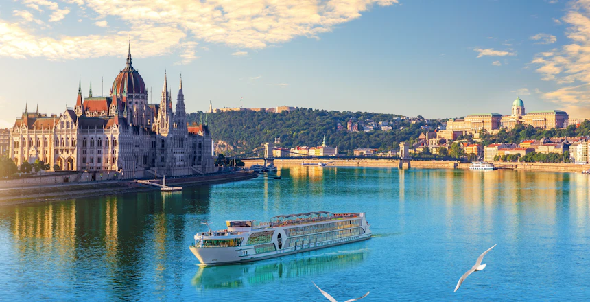 Aftenvy af Ungarns parlament ved Donau i Budapest med cruiseskibe i solnedgang
