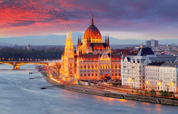 Det ungarske parlament oplyst ved solnedgang med Donau og Margaret-broen i Budapest