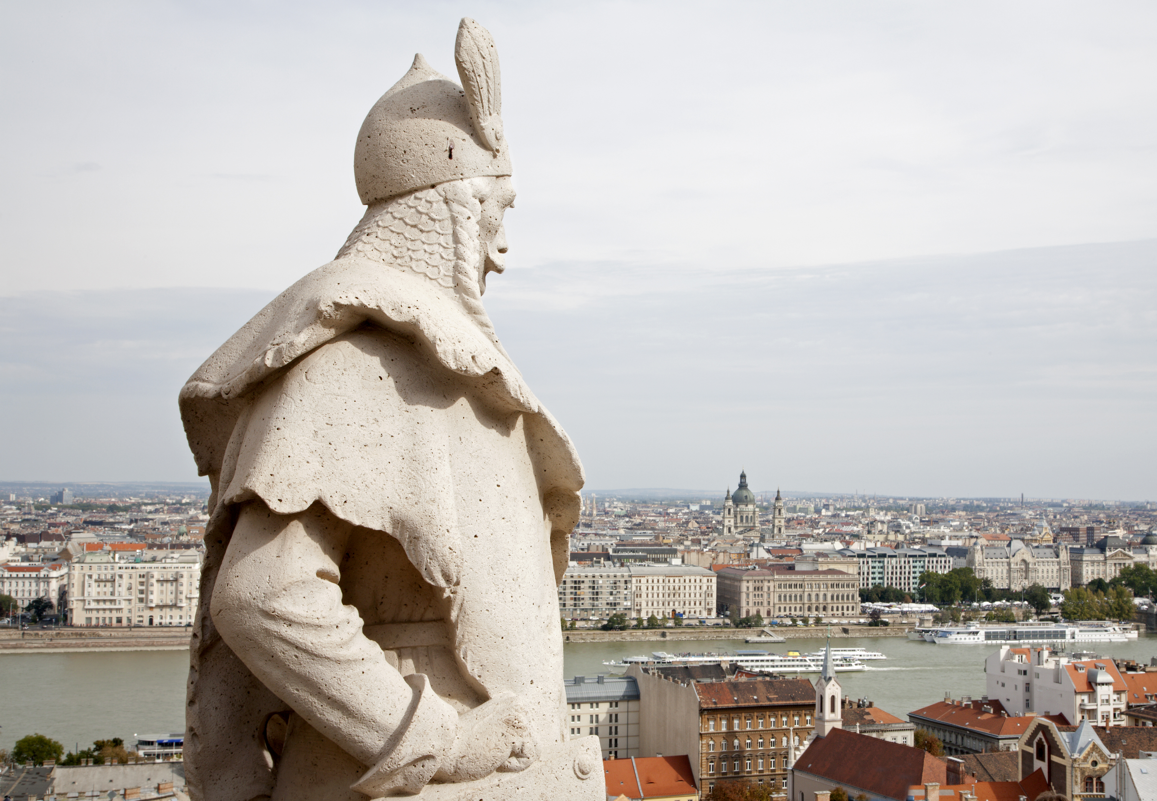 Historisk statue på Fiskerbastion med panoramaudsigt over Budapests skyline, Donau-floden og arkitektoniske perler under en skyet himmel