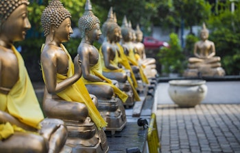 Gyldne Buddha-statuer opstillet i Seema Malaka templet i Colombo, Sri Lanka - et fredfyldt buddhistisk helligsted med smukke refleksioner i vandet og rig kulturel betydning