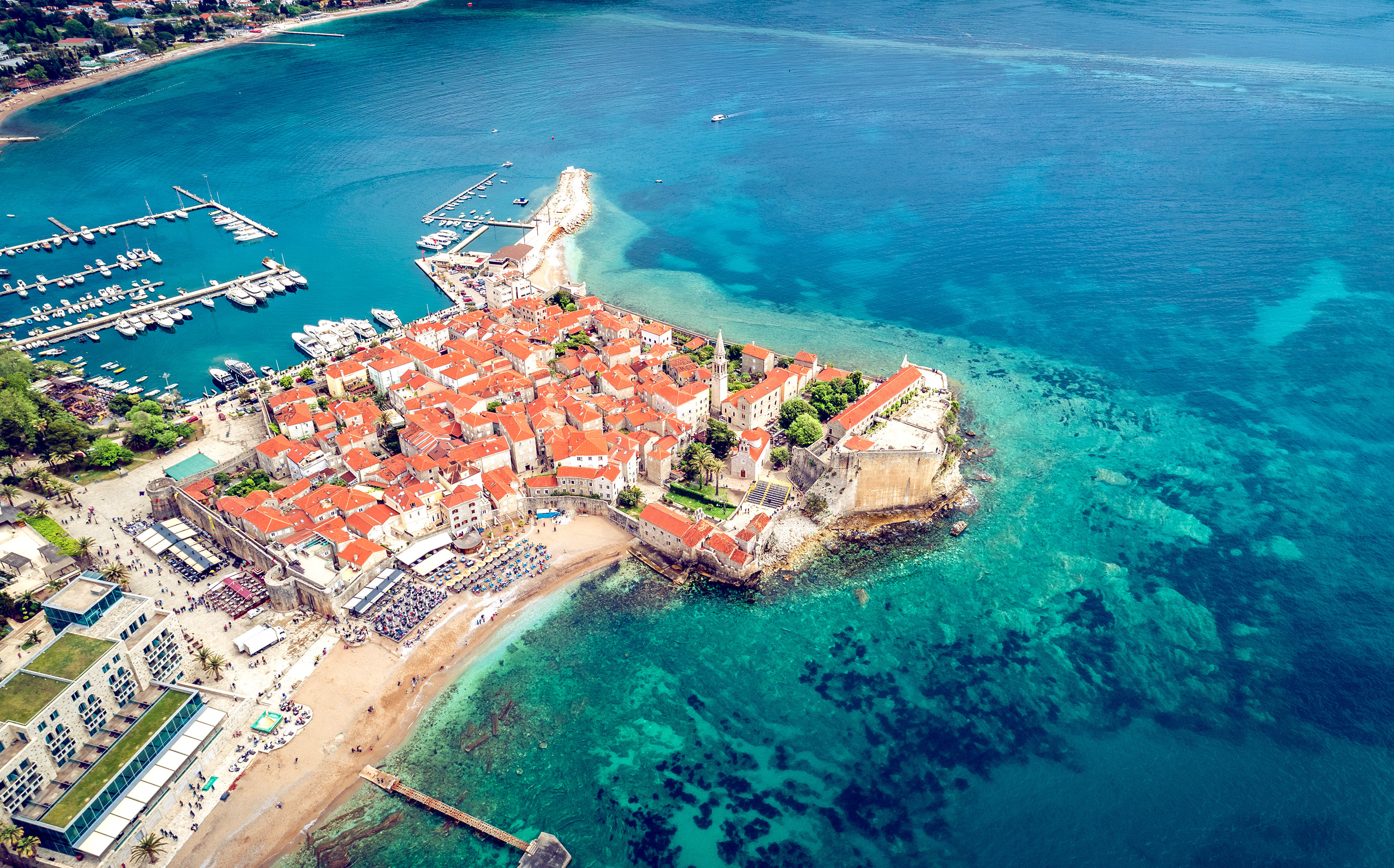 Luftfoto af Budva gamle by med middelalderlige mure og det krystalklare Adriaterhav i Montenegro