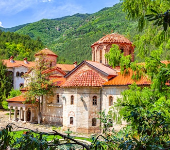 Historisk byzantinsk kloster med røde tegltage i grønne bjerge - kulturel rejseoplevelse