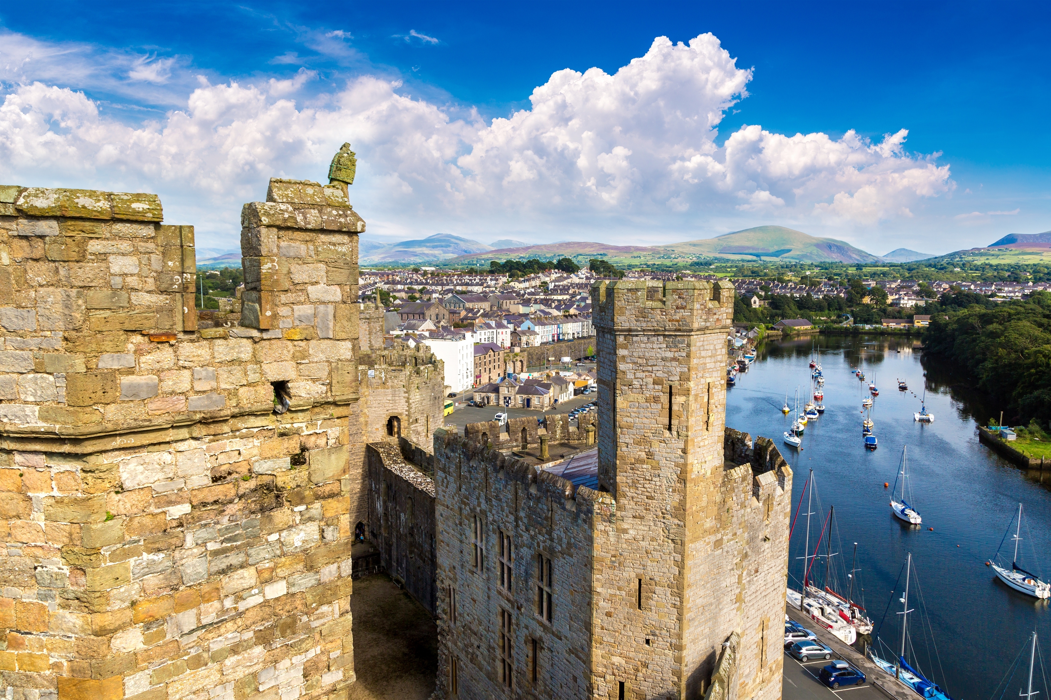 En smuk udsigt over Caernarfon Borg i Wales om sommeren, der viser den middelalderlige arkitektur og naturskønne omgivelser.