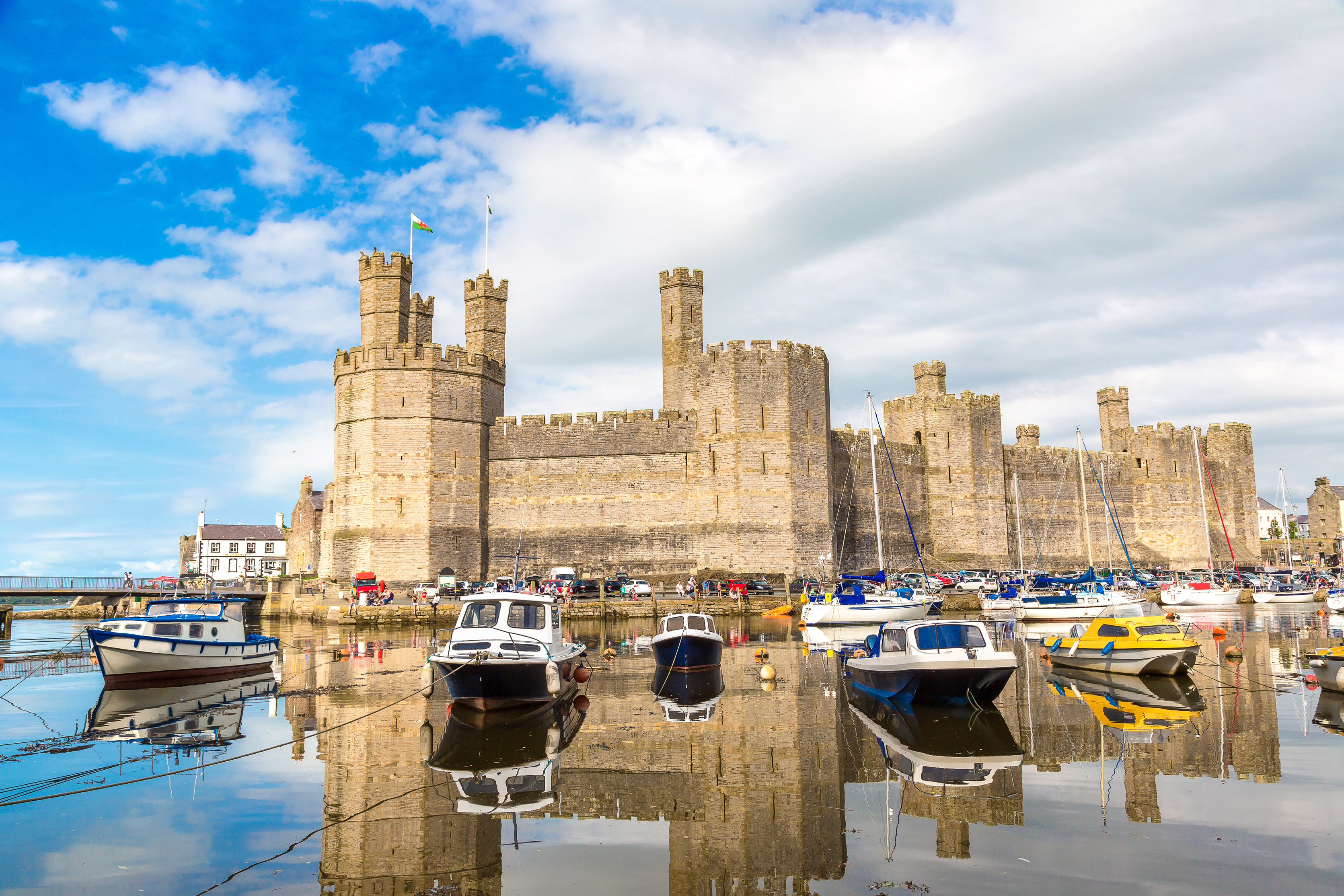 Historiske Caernarfon Slot med middelalderlige taarne og baade i havnen i Nordwales