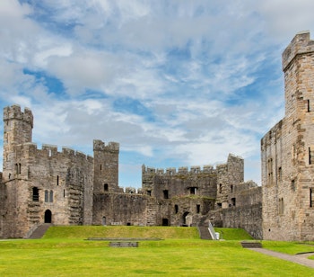 Imponerende Caernarfon Slot i Wales, en historisk fæstning fra middelalderen med stentårne og borggård, UNESCO verdensarv