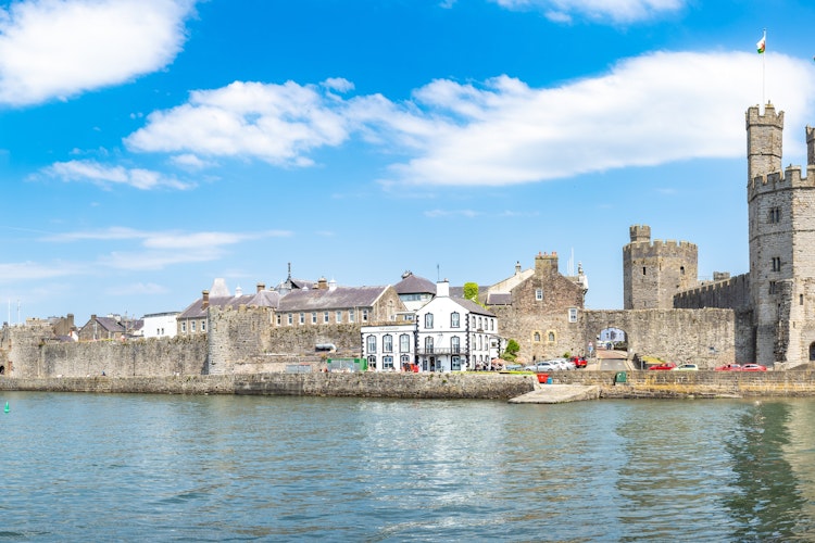 Caernarfon Slot i Wales - middelalderborg ved kysten på solskinsdag