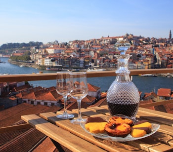 Bord med traditionelle portugisiske lækkerier og forfriskninger med smuk udsigt over Douro-floden i Porto