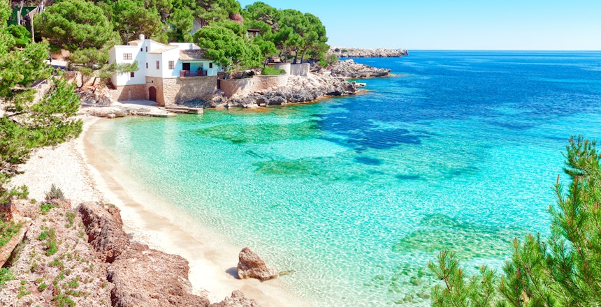 Den maleriske Cala Gat strand med krystalklart turkisblåt vand omgivet af fyrretræer på Mallorca