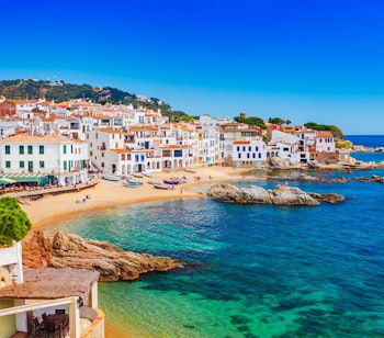 Idyllisk udsigt over fiskerlandsbyen Calella de Palafrugell ved Costa Brava med traditionelle hvide middelhavsbyggerier, der omkranser en bugt med turkisblåt vand og sandstrand i Catalonien, Spanien