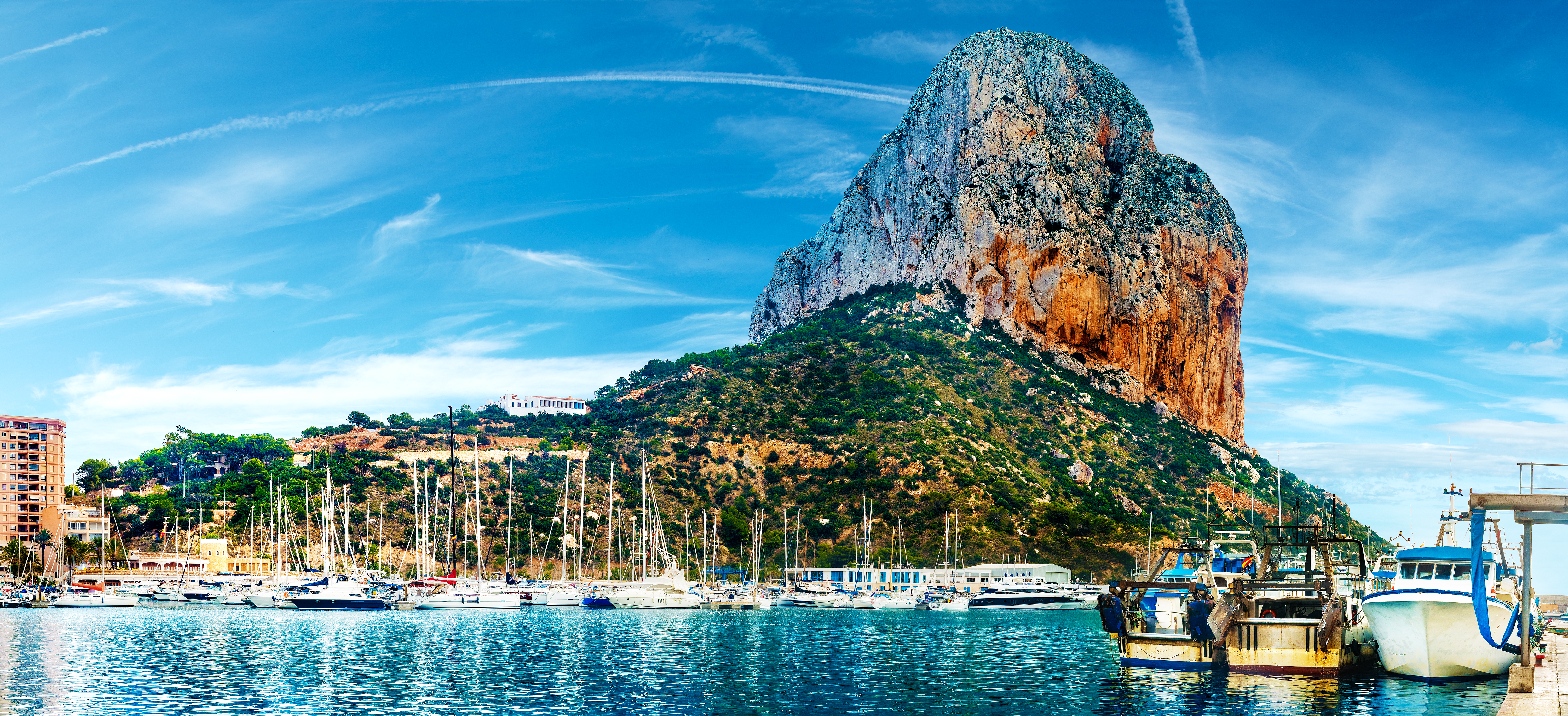 Betagende solnedgang over stranden i Calpe med den majestætiske Penon de Ifach-klippe, Middelhavets azurblå vand og kystbyens charmerende panorama i Alicante, Spanien