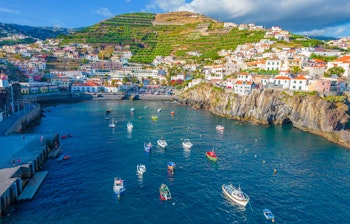 Luftfoto af den farverige fiskerlandsby Camara de Lobos nær Funchal på Madeira med mange små både i den blå bugt