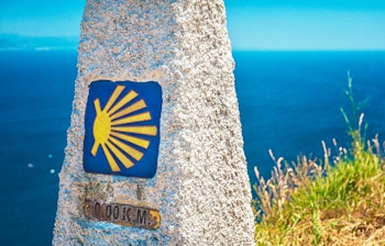 Historisk milepæl ved Cabo Finisterre fyrtårn markerer 0 km punktet på Camino de Santiago pilgrimsruten i Galicien, Spanien