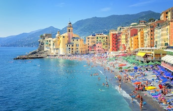 Idyllisk sandstrand i den charmerende kystby Camogli nær Genova med farverige historiske bygninger og fiskerbåde ved det azurblå Middelhav i Ligurien