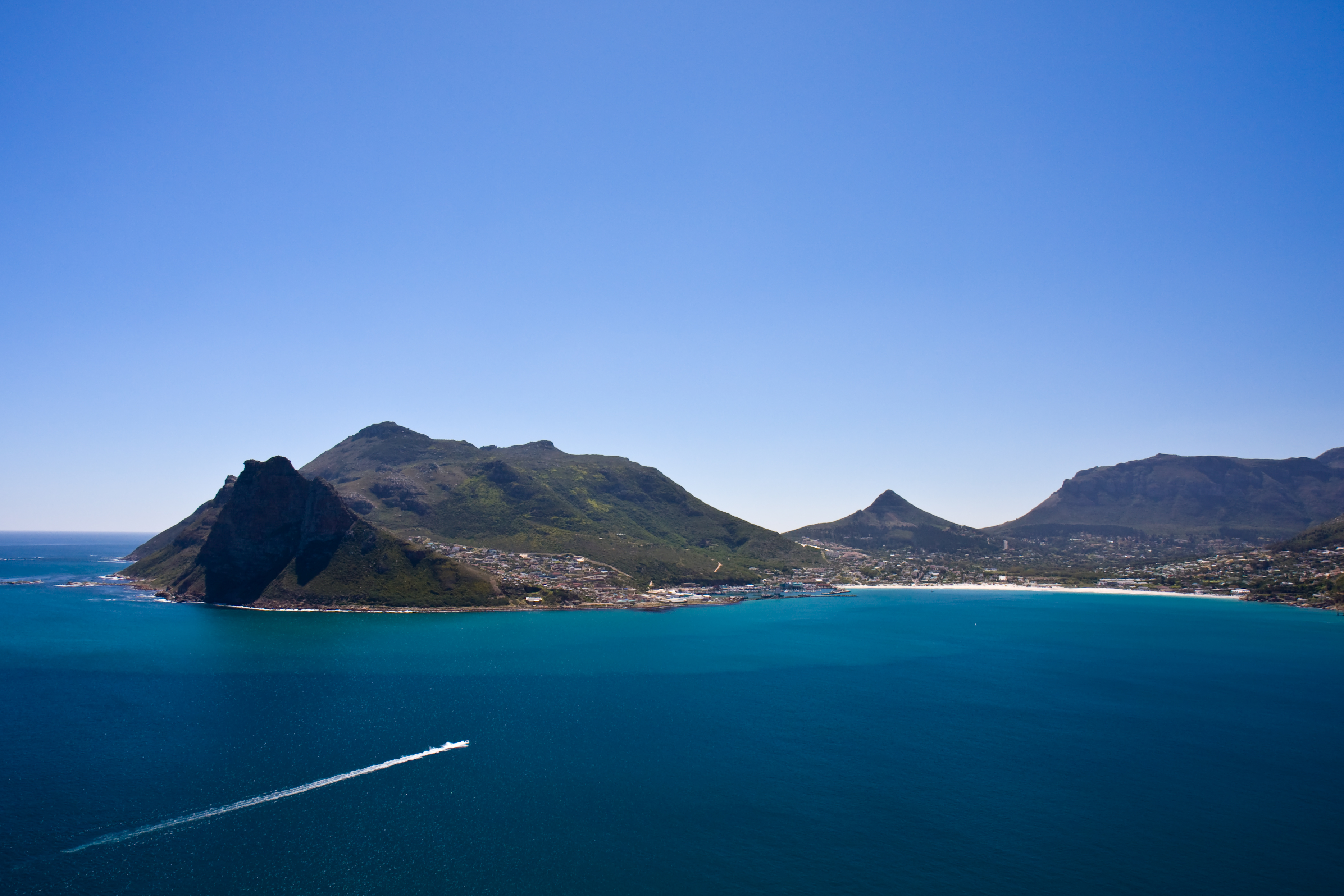 Betagende udsigt over Camps Bay kysten i Cape Town med turkisblåt hav og majestætiske bjerge i baggrunden