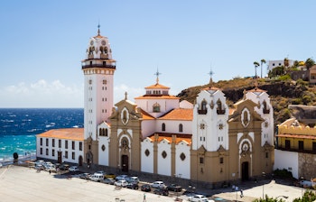 Den historiske Candelaria Kirke med udsigt over havet på Tenerife, De Kanariske Øer, med sin karakteristiske hvide facade og tvillingetårne mod den blå himmel