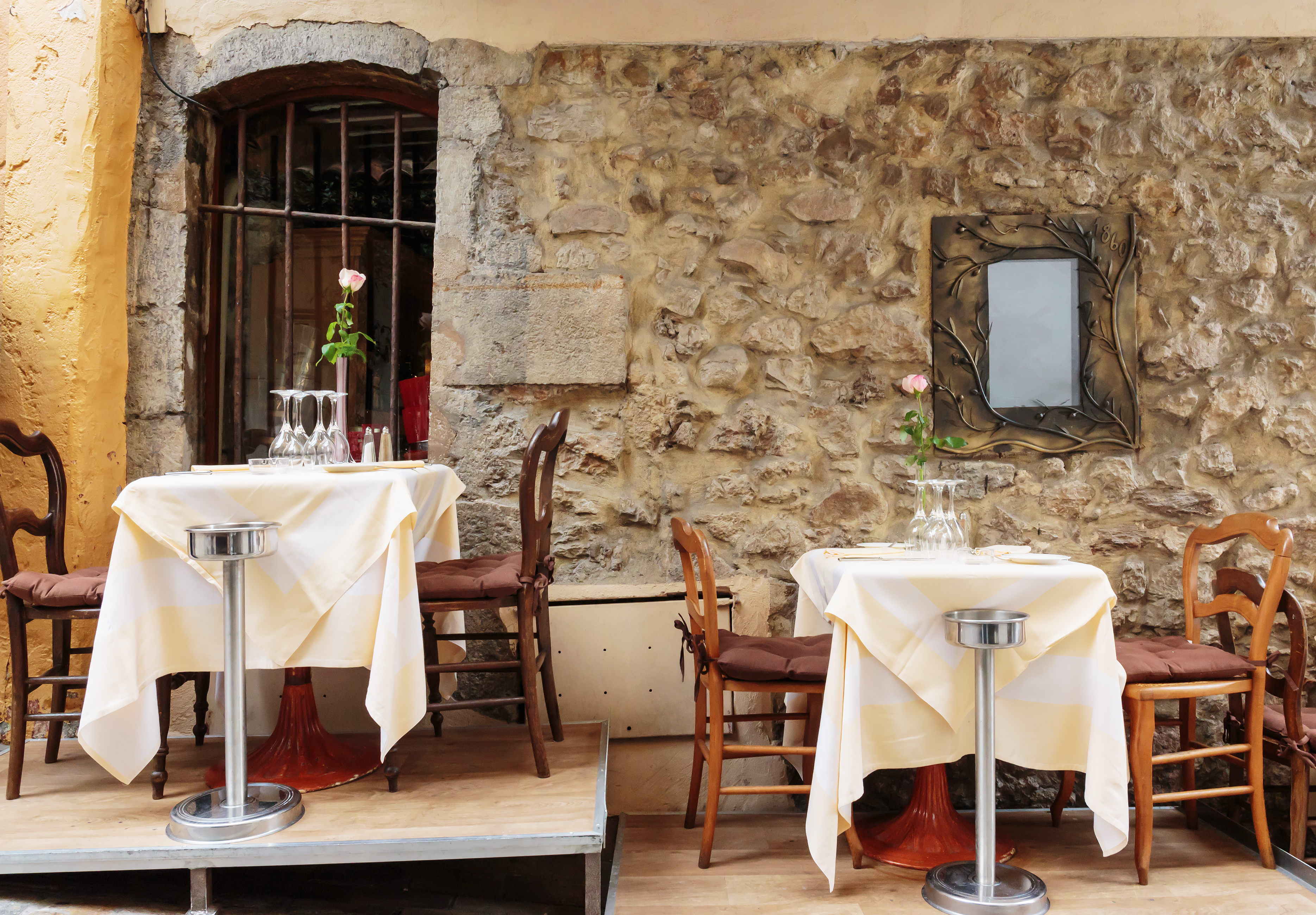 Charmerende udendørs restaurant med hvide duge og gamle stenmure i Cannes på den franske riviera