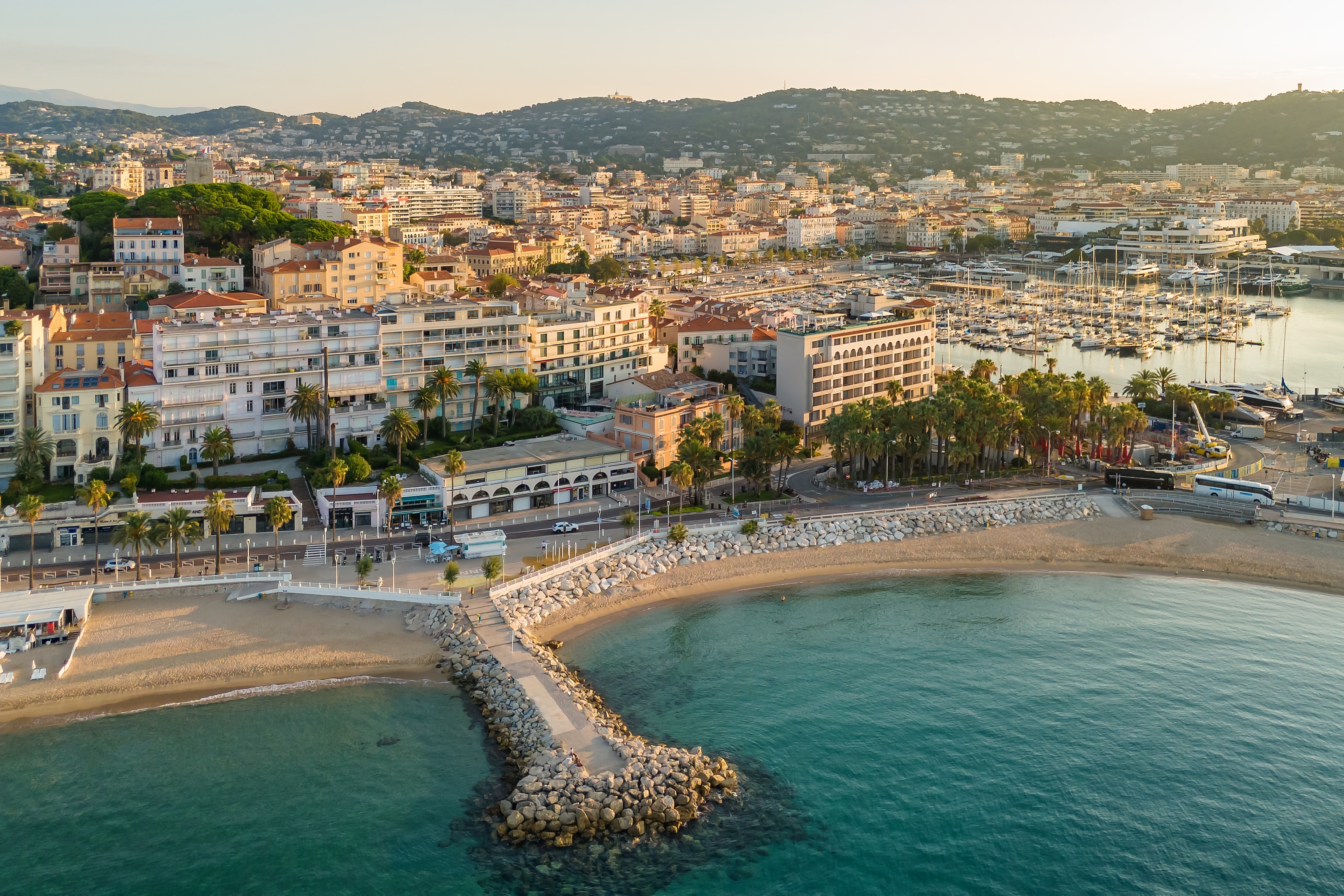 Luftfoto af Cannes strand ved solopgang med luksuriøse hoteller, marina og turkisblåt Middelhav langs den franske riviera