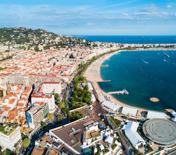 Betagende luftpanorama over Cannes med den gyldne sandstrand langs La Croisette, luksusyachter i havnen og det azurblå Middelhav