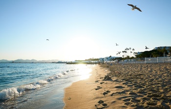 Idyllisk sandstrand med det azurblå Middelhav og klar blå himmel på en solrig sommerdag i Cannes på den franske riviera