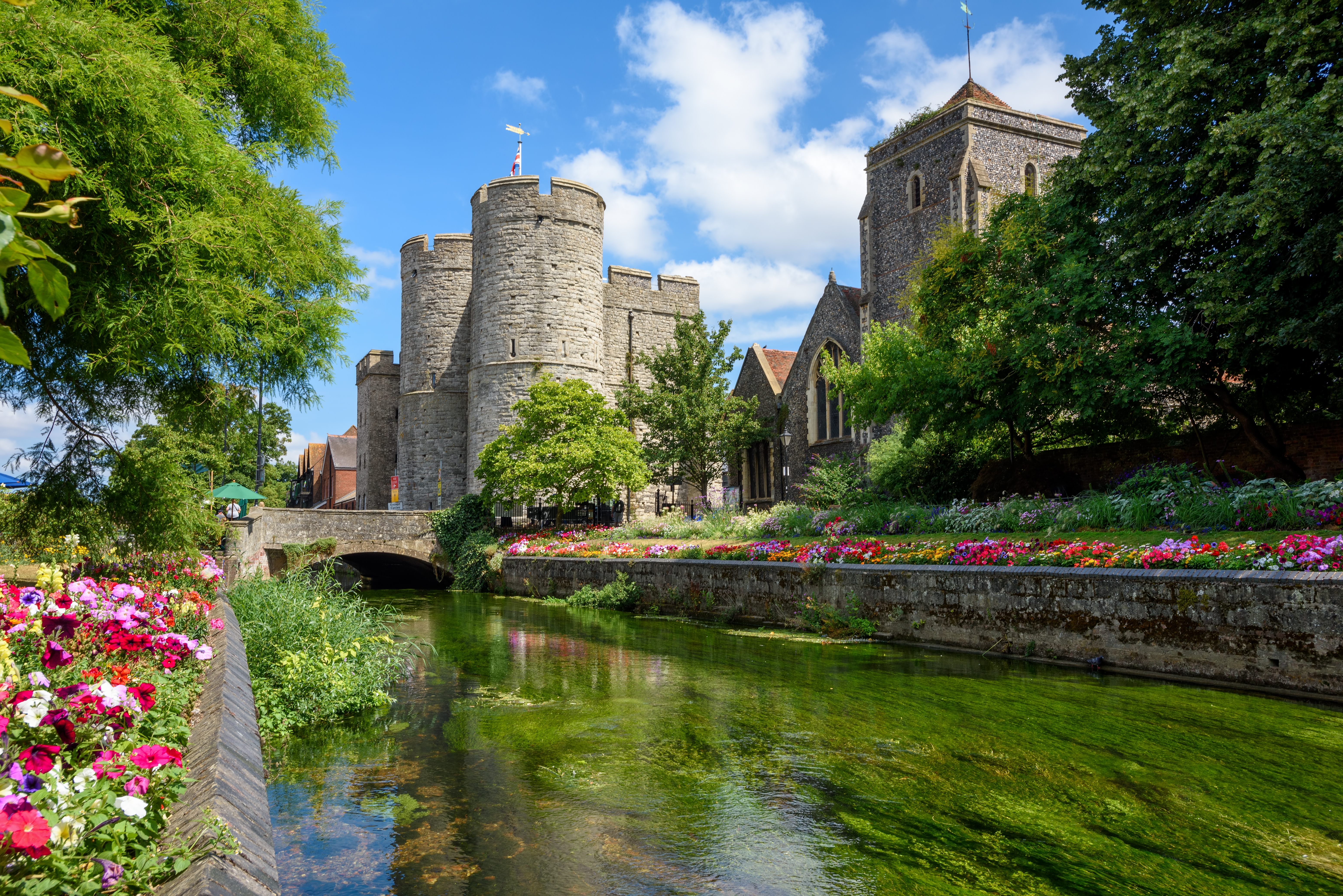 Middelalderlig normannisk borg i Canterbury Old Town med floden Stour der løber gennem farverige blomsterhaver en solrig sommerdag i Kent, England