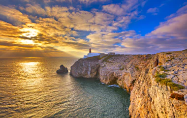 Solnedgang ved Cape St. Vincent fyrtårn og dramatiske klipper i Portugal