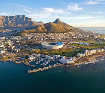 Luftfoto af Cape Town med Table Mountain og Lions Head i baggrunden, Cape Town Stadium og havneområdet langs Atlanterhavskysten i Sydafrika