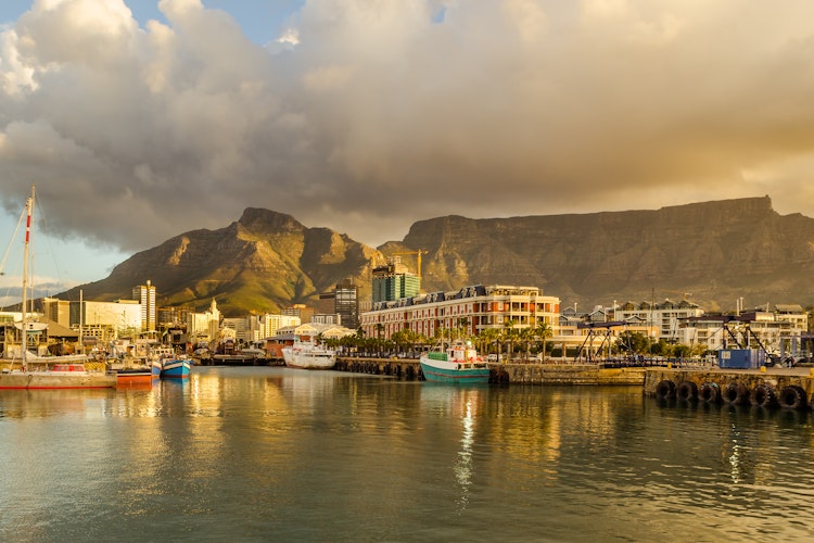 Betagende solnedgang over Victoria & Alfred Waterfront i Cape Town med både i havnen, det sydafrikanske flag og Table Mountain i baggrunden