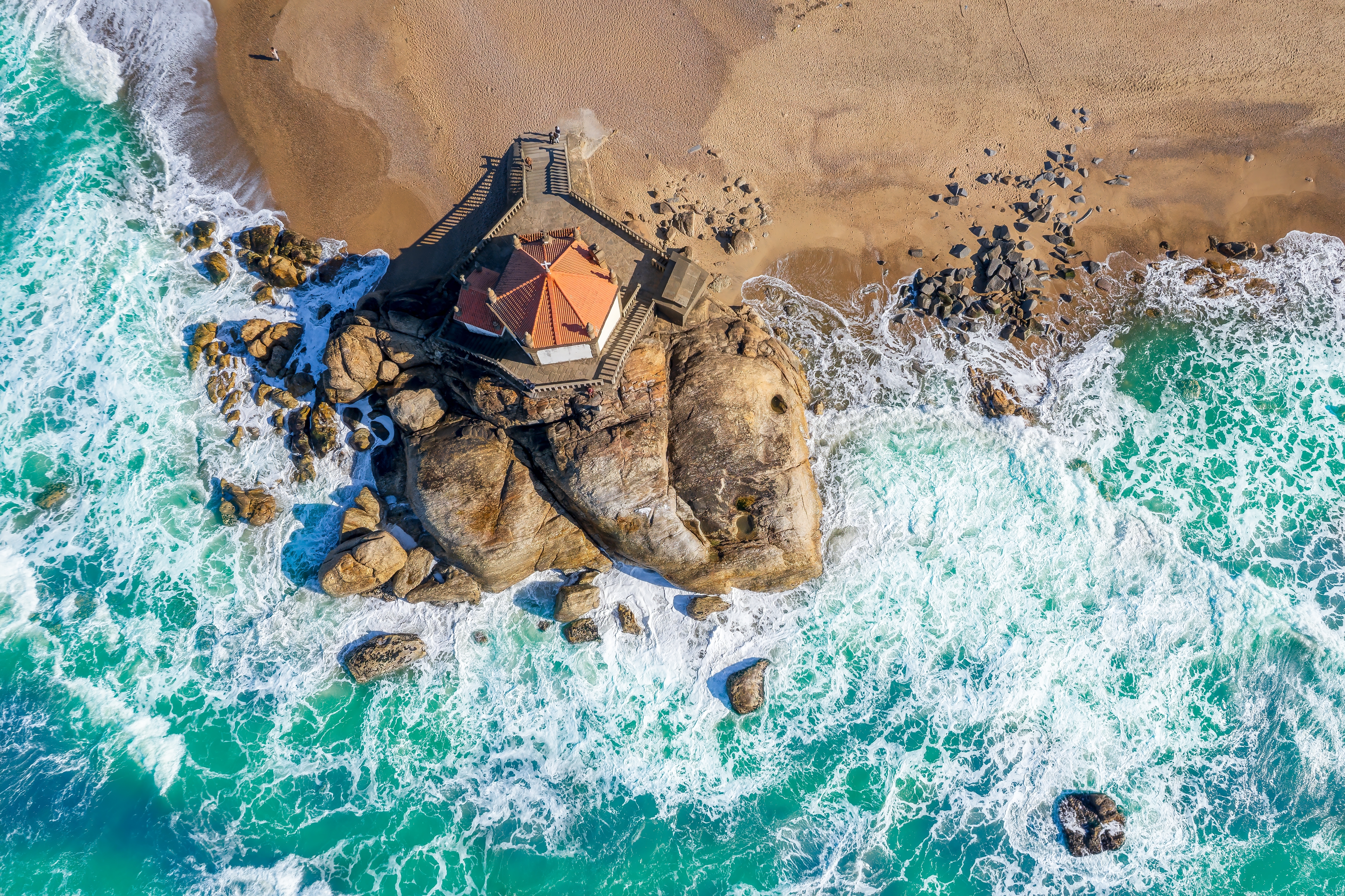 Luftfoto af det historiske kapel Capela do Senhor da Pedra bygget på klipper i Atlanterhavet ved Miramar-stranden syd for Porto