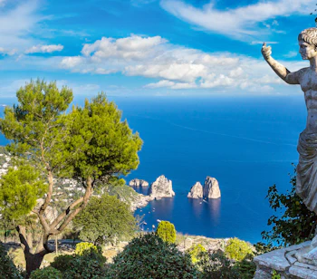 Smuk panoramaudsigt over Capri ø med antik romersk statue og de berømte Faraglioni klipper i det turkisblå Middelhav
