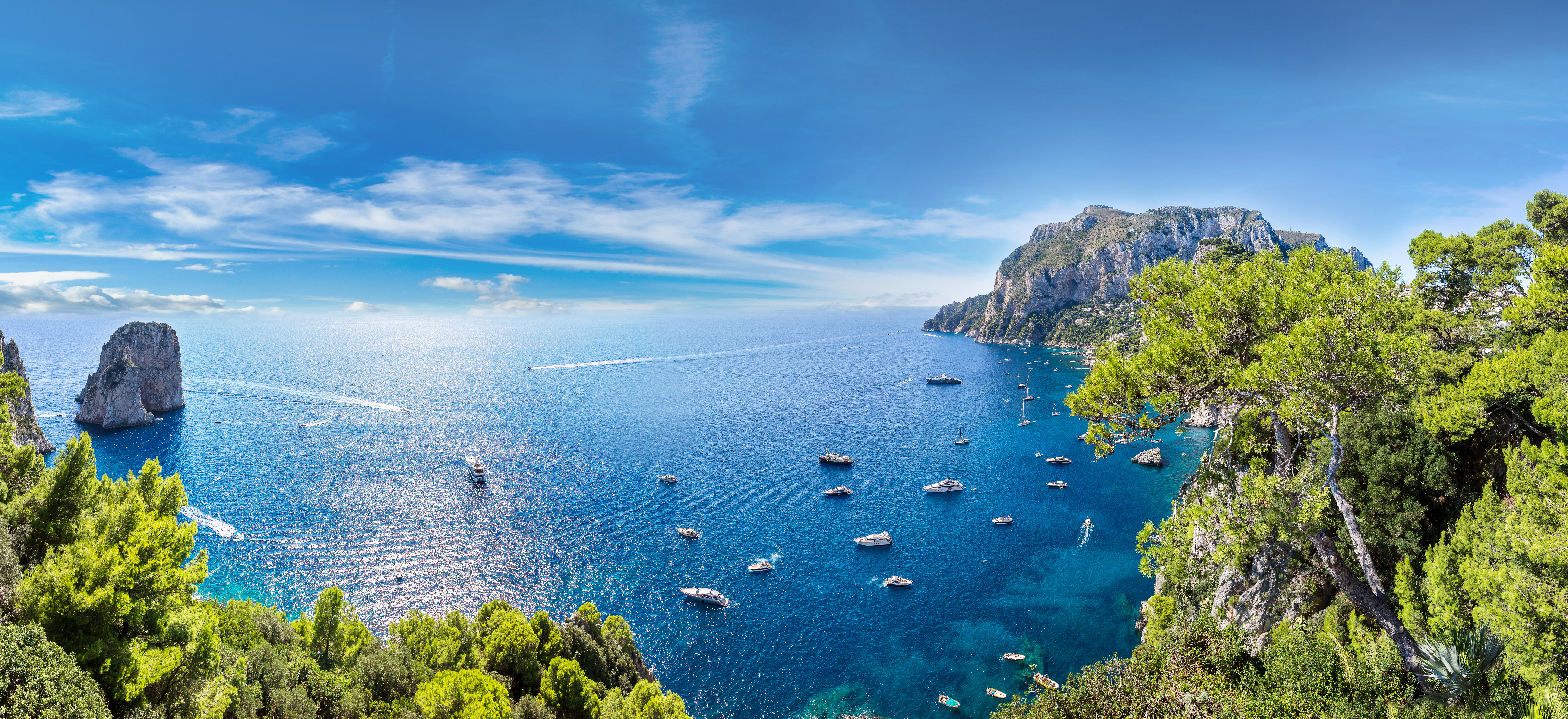 Panoramisk luftfoto af Capri-øen med azurblåt Middelhav, dramatiske klipper og malerisk marina på en solrig sommerdag i Italien