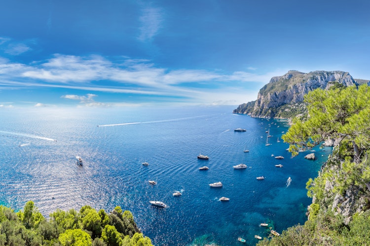 Panoramisk luftfoto af Capri-øen med azurblåt Middelhav, dramatiske klipper og malerisk marina på en solrig sommerdag i Italien