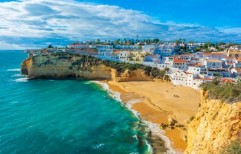 Malerisk udsigt over Carvoeiro i Algarve med gyldne klipper, turkisblåt hav og charmerende hvide bygninger ved Atlanterhavskysten