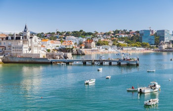 Malerisk udsigt over Cascais kystby med farverige bygninger, marina og azurblåt hav på Portugals atlanterhavskyst