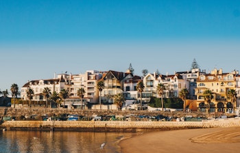 Idyllisk udsigt over Cascais-stranden med traditionelle bygninger og Santa Marta-fyrtårnet ved Lissabons kyst i Portugal