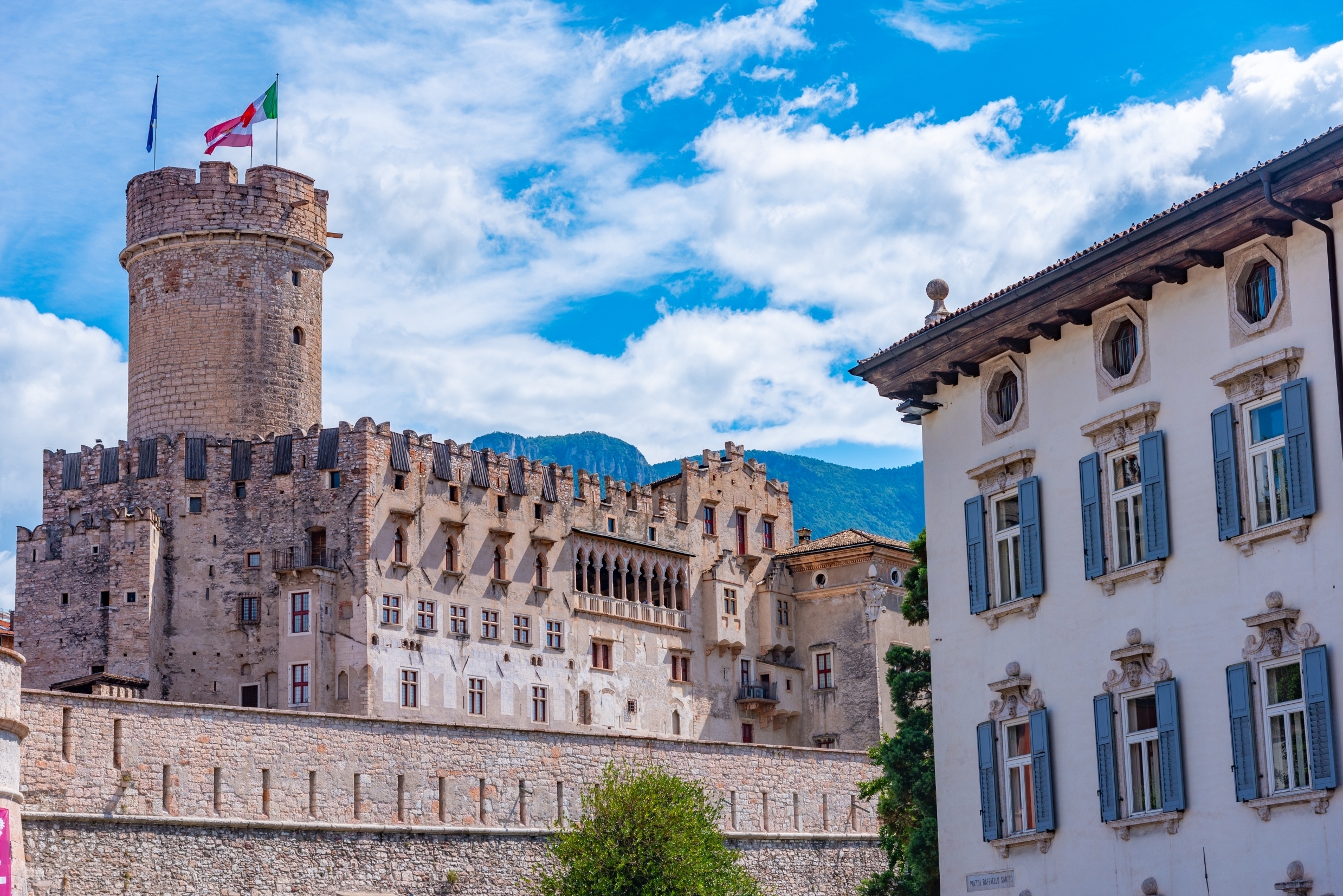 Middelalderborgen Castello del Buonconsiglio med italienske flag i Trento, Italien, med bjergene i baggrunden