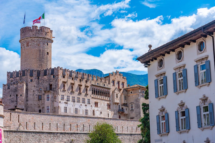 Middelalderborgen Castello del Buonconsiglio med italienske flag i Trento, Italien, med bjergene i baggrunden